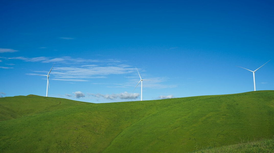 Wind turbines on green hills under a blue sky