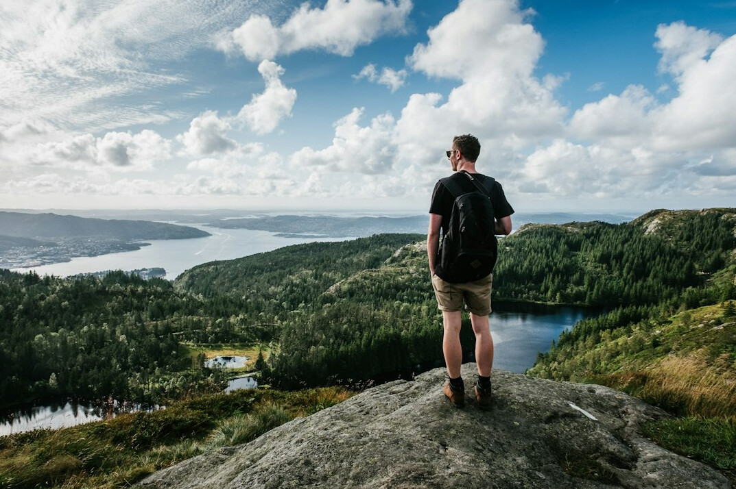 Hiker standing on a cliff overlooking mountains